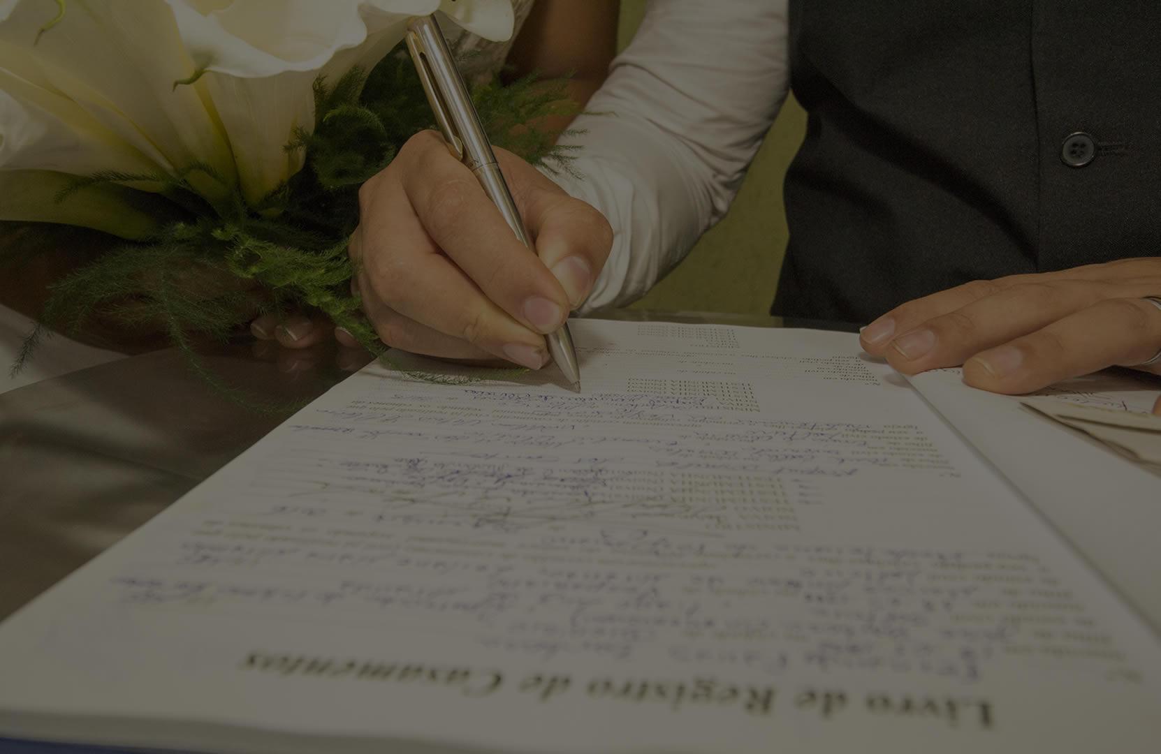 Mãos assinando livro de registro de casamento